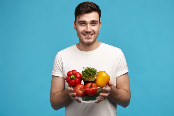 גבר מחזיק קערת ירקות כחלק מתפריט דיאטה לגבר