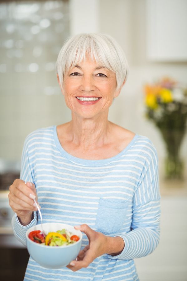 אישה בגיל המעבר מחזיקה קערה עם ירקות חתוכים