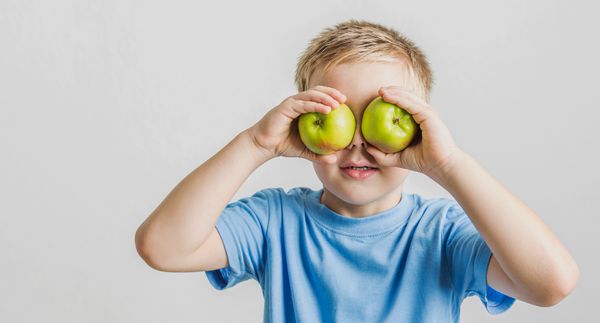 ילד מחזיק ב שני תפוחים צמודים לפנים בצורת משקפת