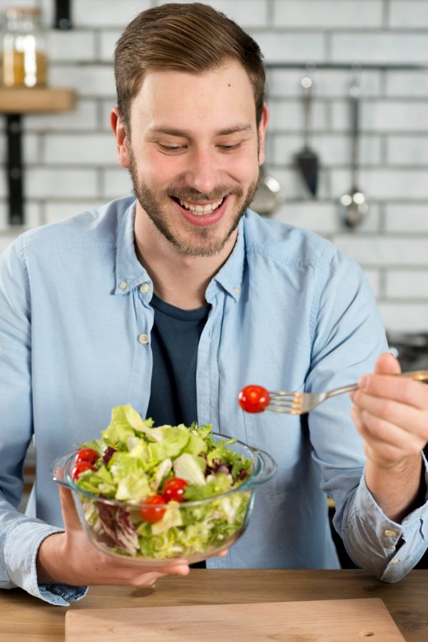 גבר אוכל קערת ירקות כחלק מתפריט דיאטה לגבר