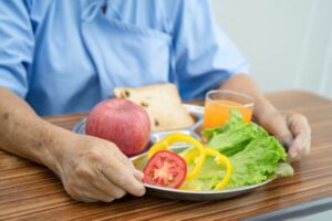 אדם מחזיק בארוחת בוקר בריאה עם ירקות, תפוח ופרוסת לחם