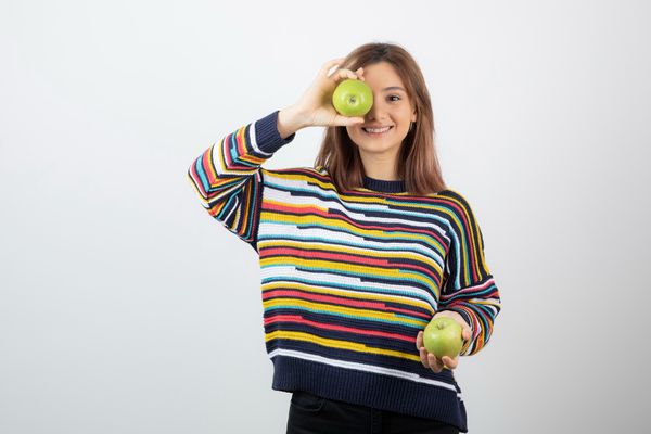 נערה מחייכת שמחזיקה ב2 תפוחים(תפוח בכל יד)